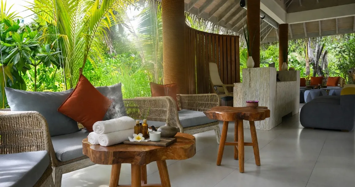 The REVIVE Spa lounge, open to the tropical garden, with its sofas, timber tables and rolled towels.