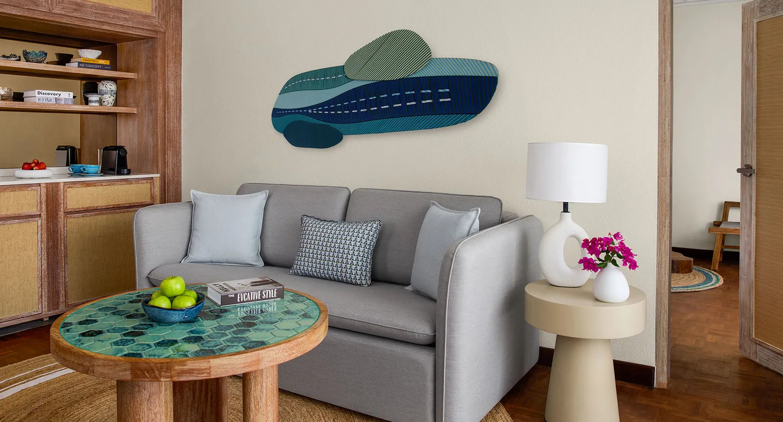 The separate living room of a pool villa: the grey sofa, the green-tiled table and the coffee corner.