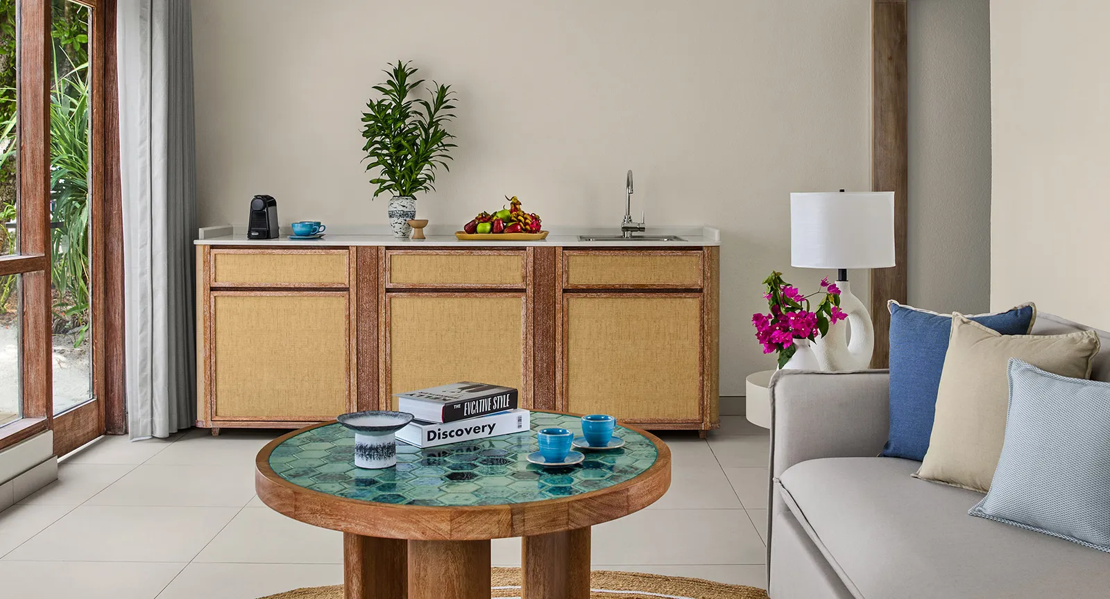 The 2-bedroom villa’s living room: the round tiled table, the sofa and the counter with its sink and coffee machine.