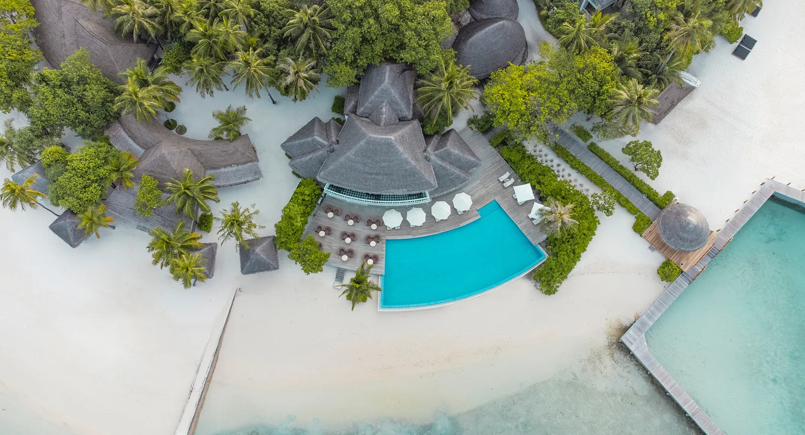 The infinity pool from above, between the thatched restaurant, the loungers and the lagoon.