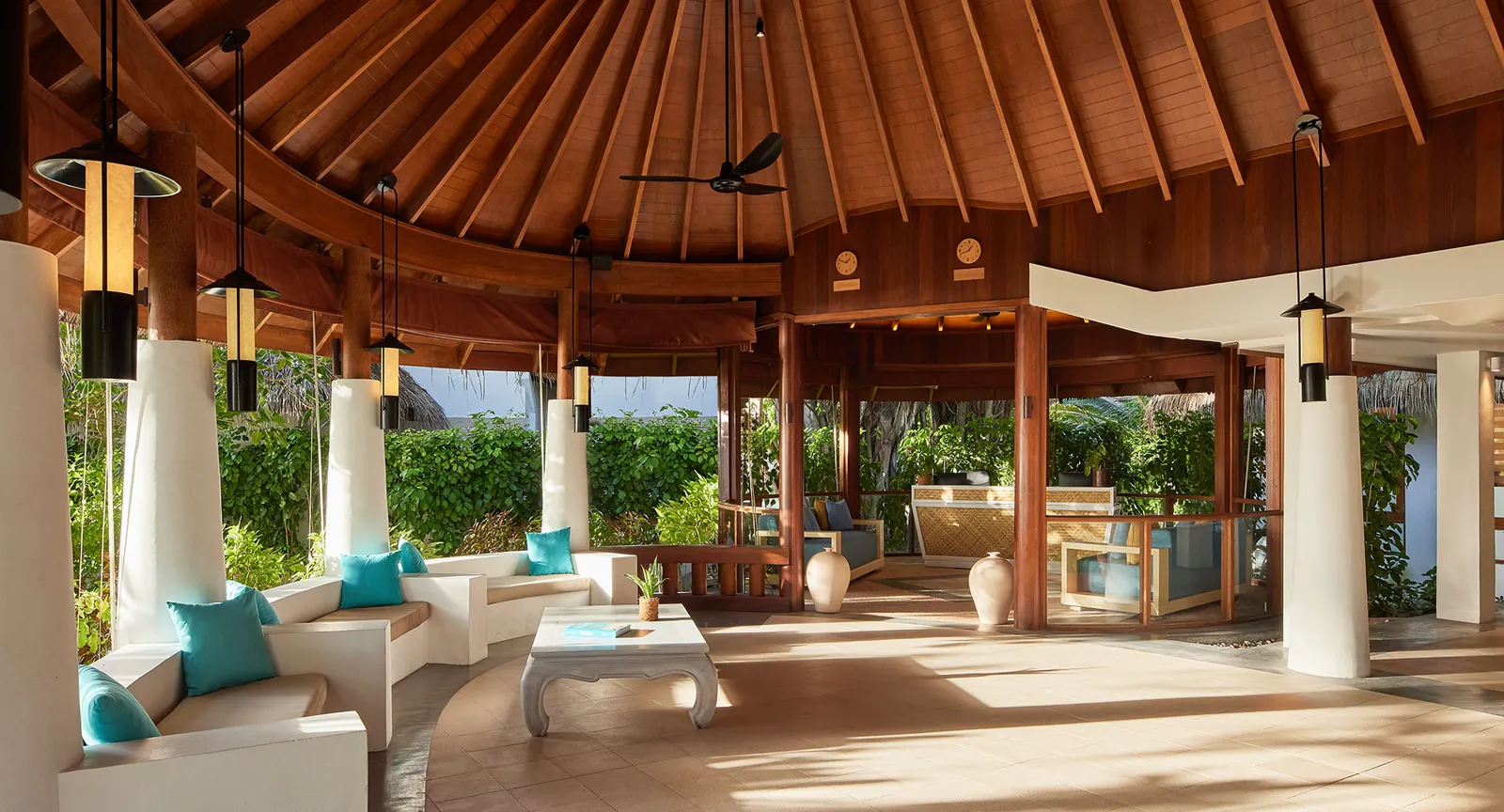 Reception under the great timber dome, with white sofas and turquoise cushions.