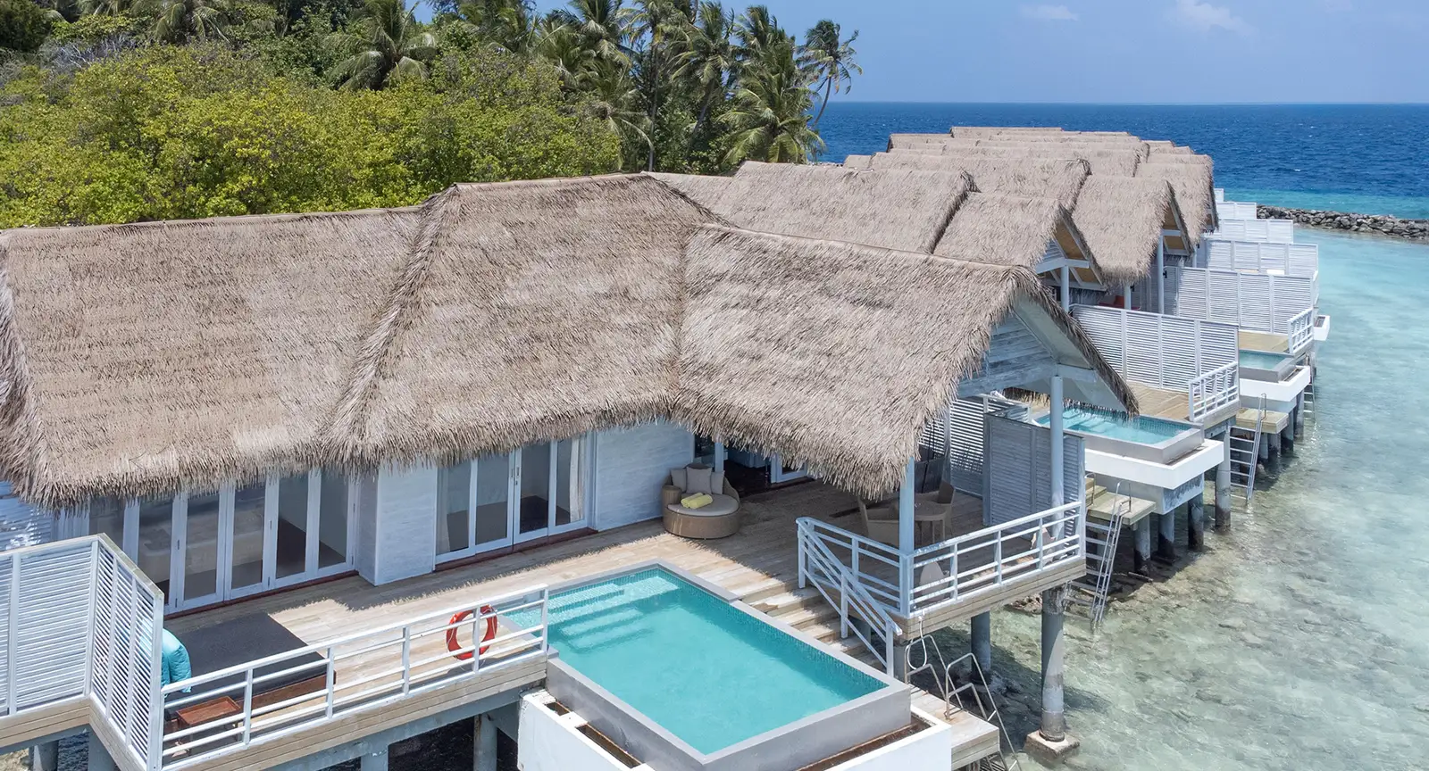 The water residences from above, with their thatched roofs, decks and a private pool over the lagoon.