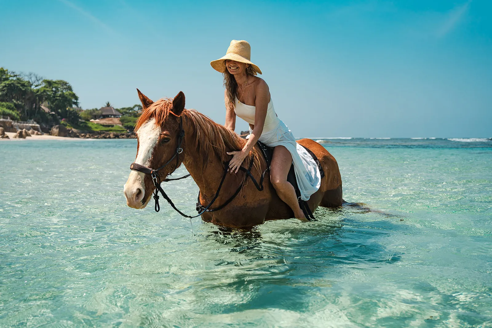 Un’ospite a cavallo nell’acqua bassa e chiara davanti alla spiaggia di Nihiwatu