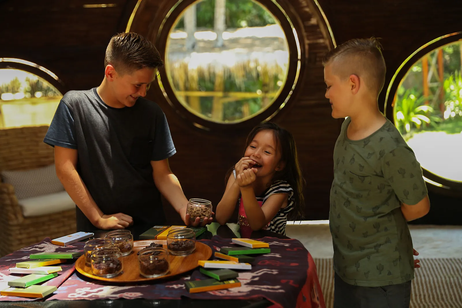 3 bambini preparano cioccolatini al Chocolate Factory, sotto le finestre rotonde