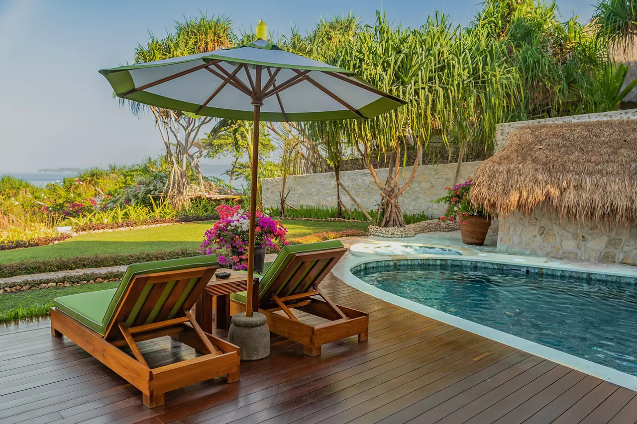 La piscina di Putri Wamoro Jungle con 2 lettini verdi sotto l’ombrellone, fra gli alberi
