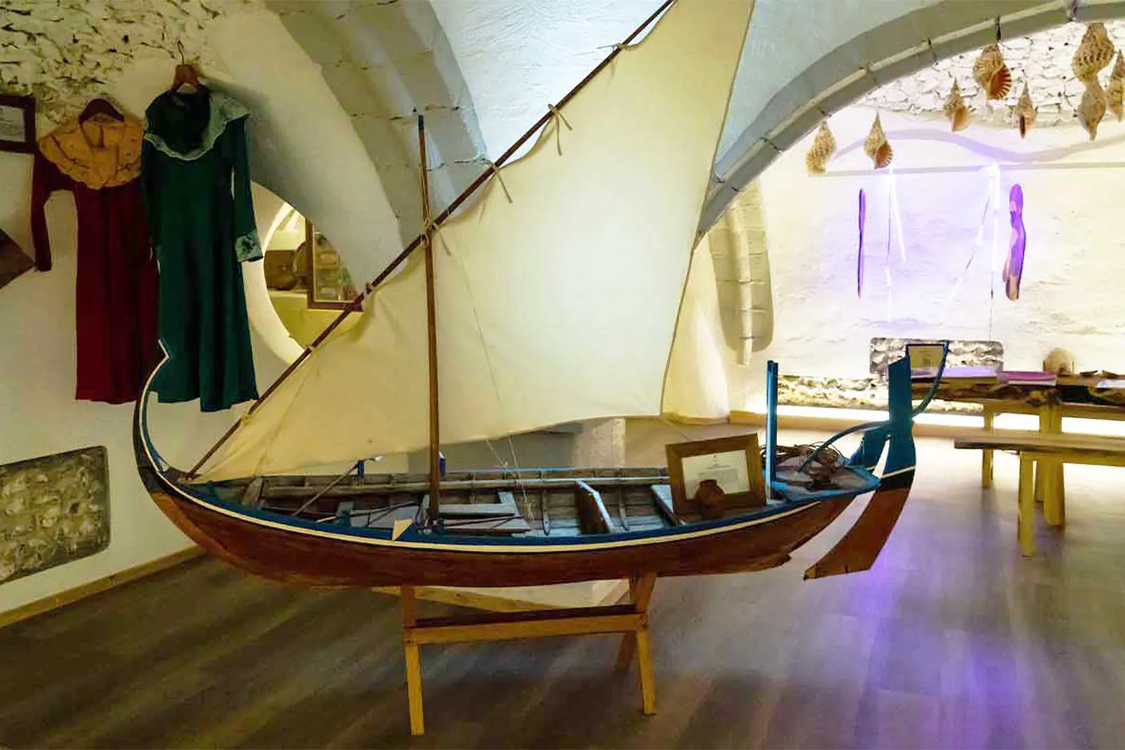 A wooden dhoni on show in the museum under the coral vault, beside Maldivian costumes.