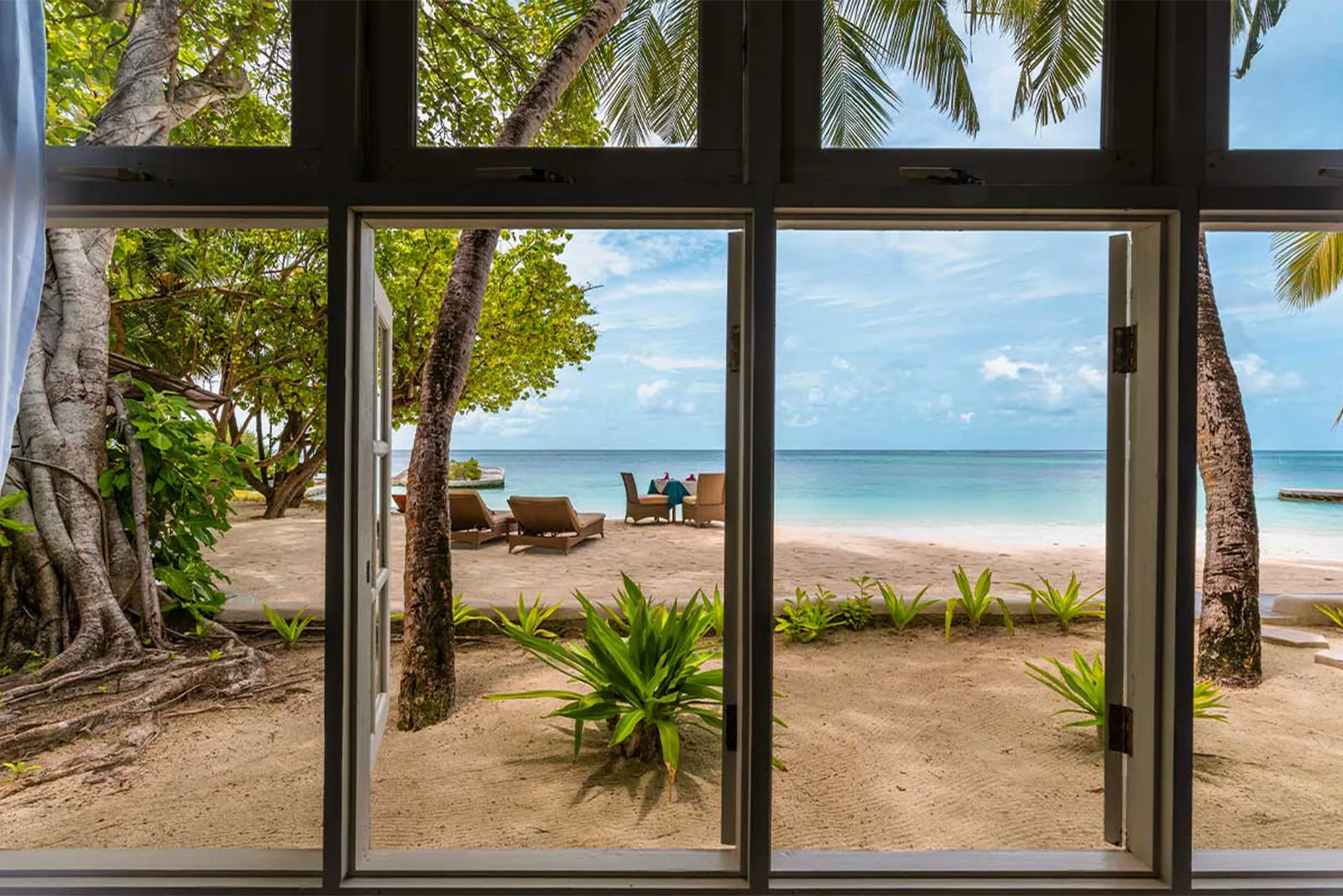 Through the Sultan Suite’s glass doors: the private beach, the loungers and the sea.