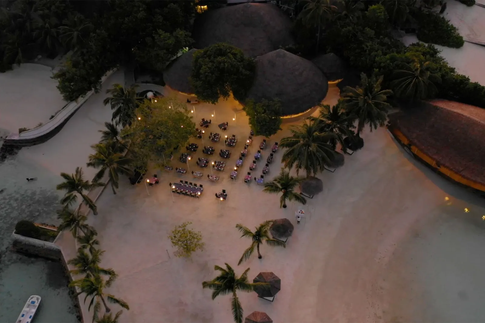 The Marco Polo restaurant at dusk from above, its tables out in the open among the palms and the thatch.