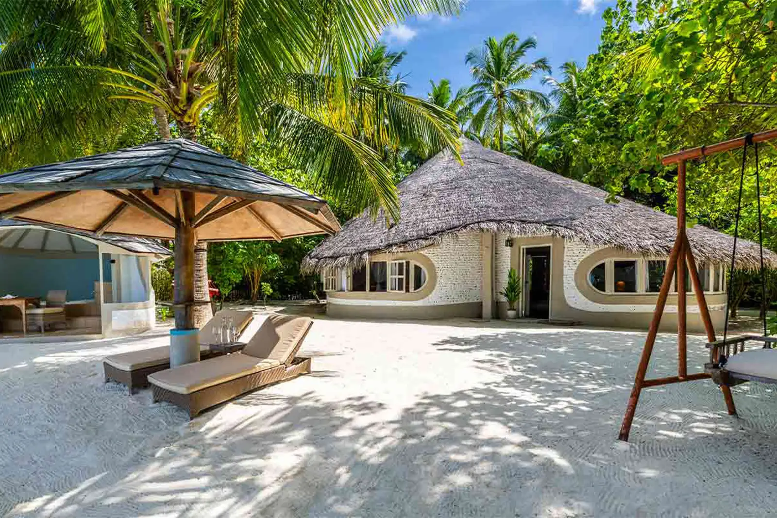 A Deluxe Beach Villa’s garden: the gazebo with its hot tub, a timber parasol, loungers and the round villa.