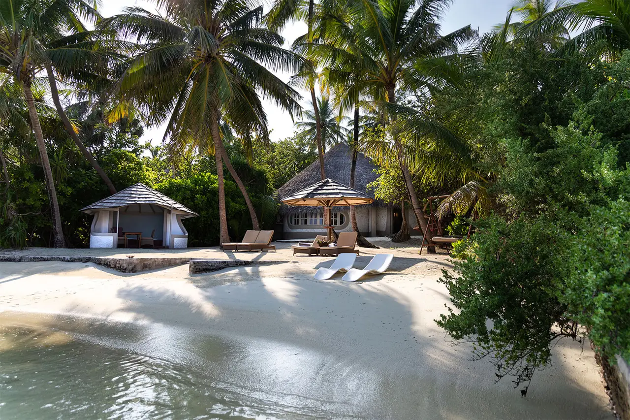 A Family Beach Villa’s private beach, with the gazebo, white loungers and the villa among the trees.