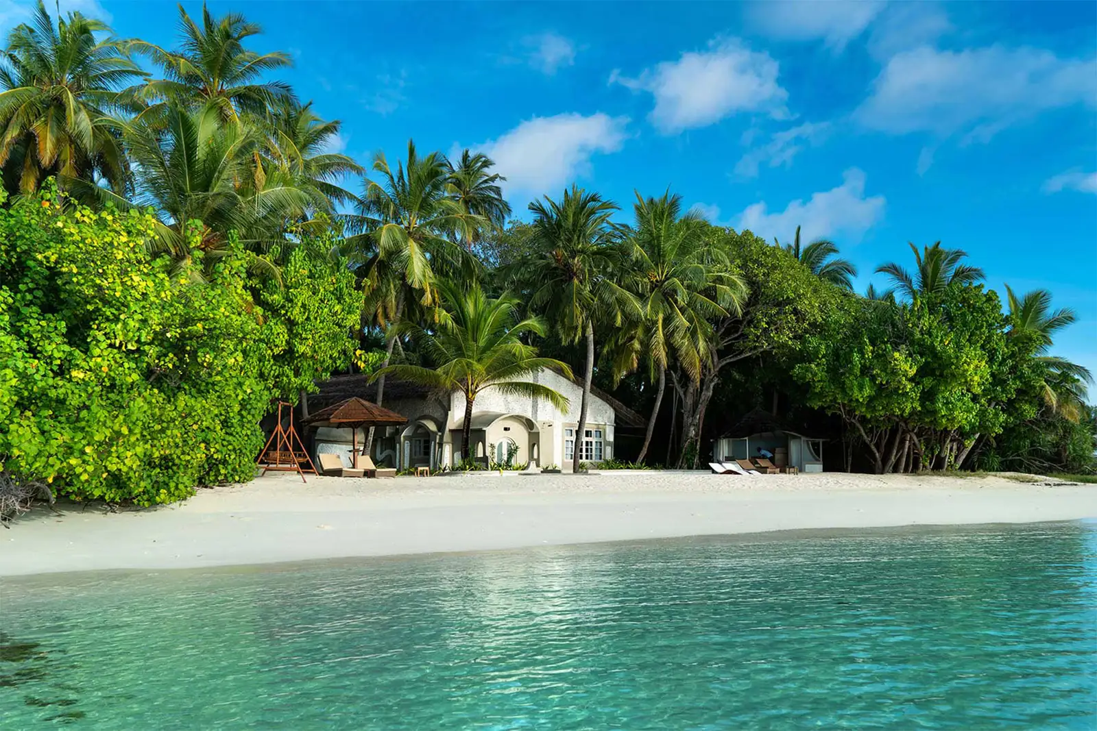 The white Sultan Suite among the palms, behind the island’s largest private beach.