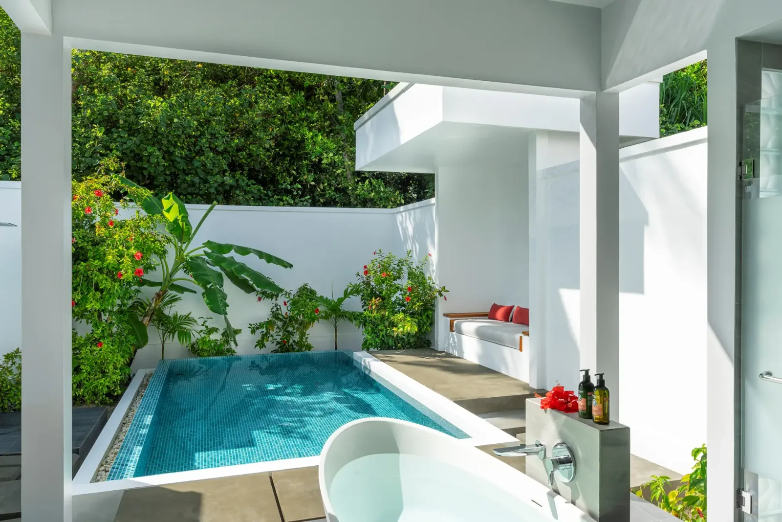 The Beach Suite with Garden Pool’s courtyard: the pool, the freestanding bath and plants around white walls.