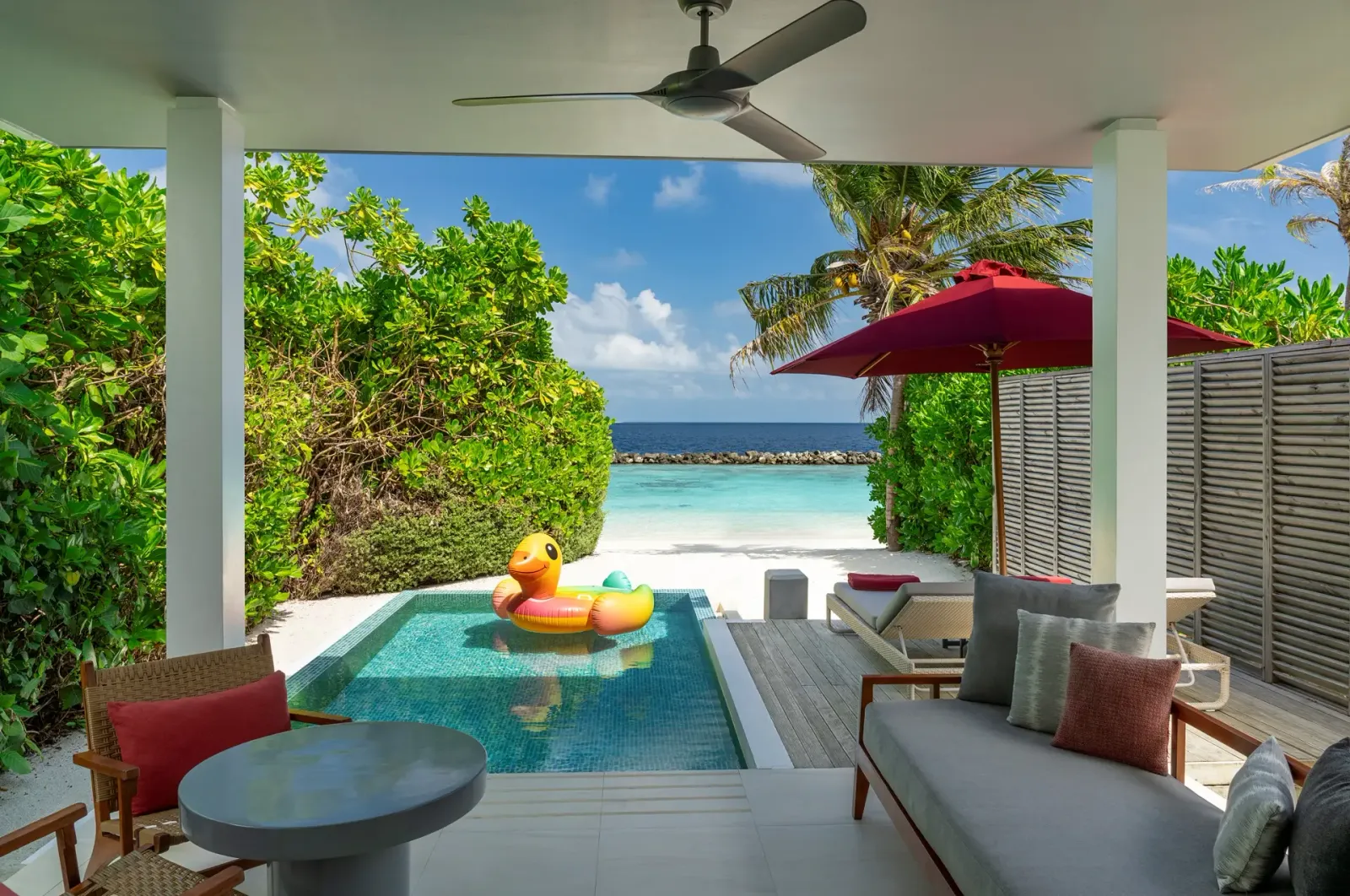 A Beach Suite with Pool’s covered terrace: the sofa, the plunge pool and the sea beyond the hedges.