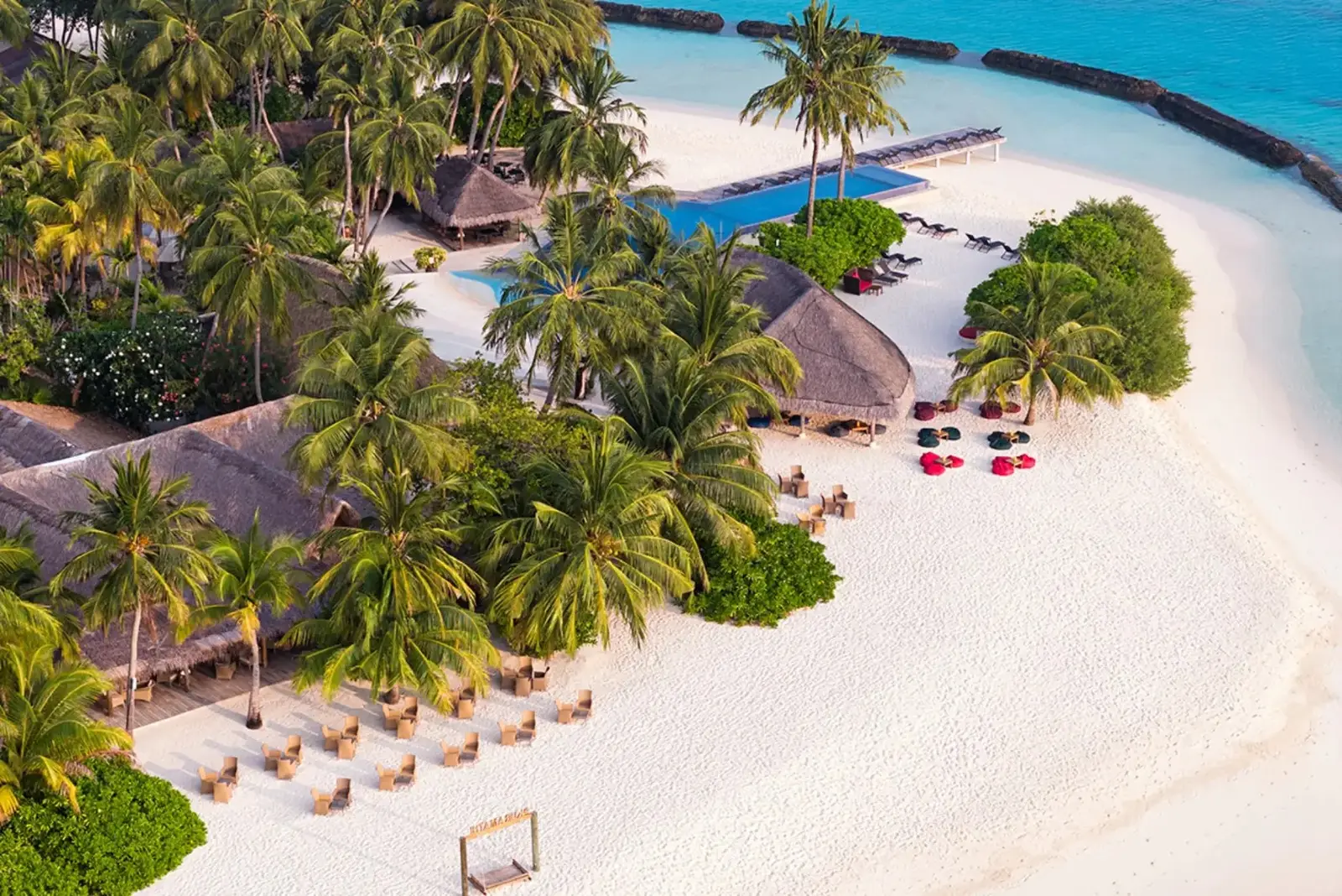The white beach and the pool from above, the bars’ tables on the sand among the palms