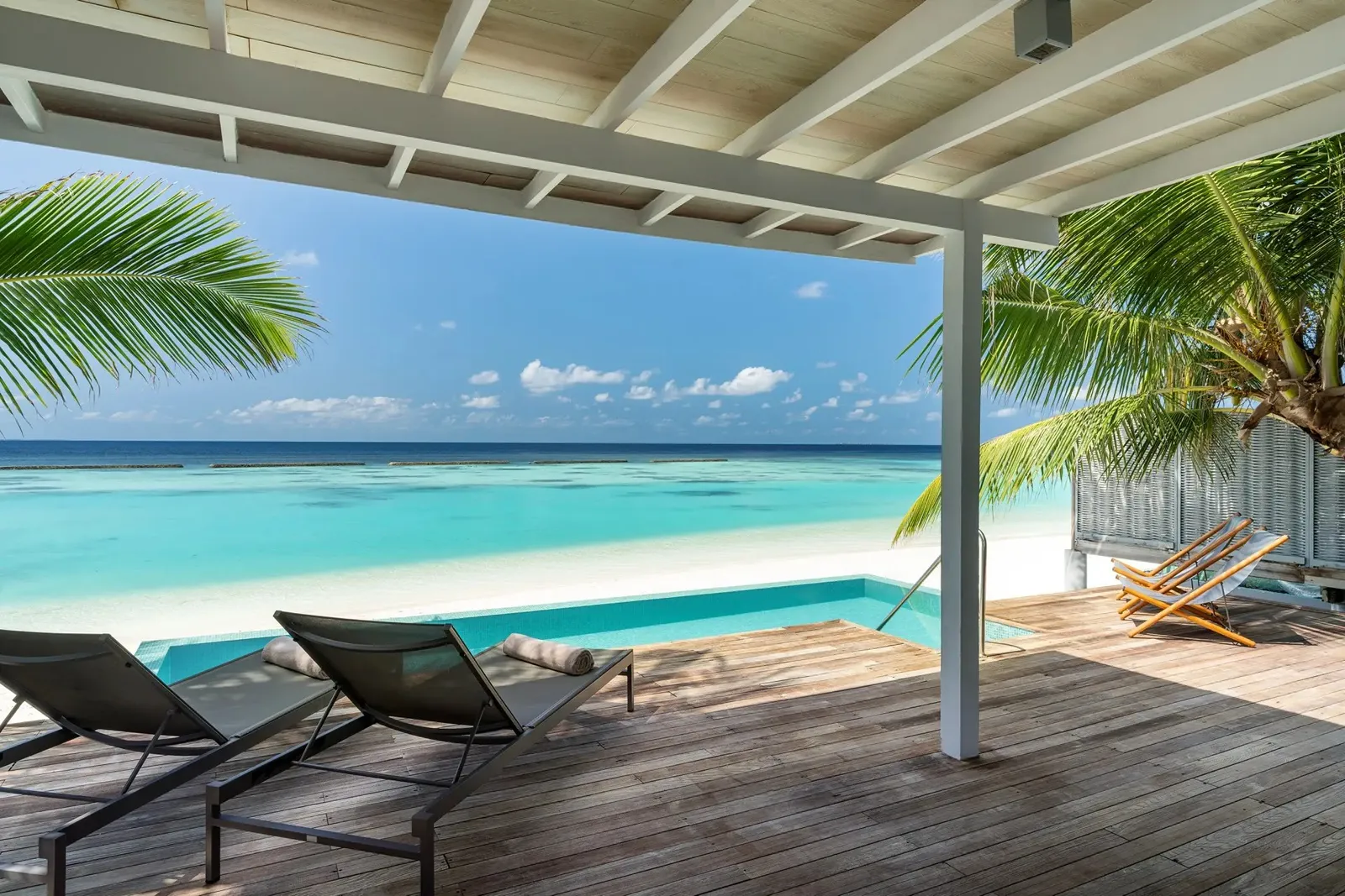 A Pool Villa’s deck, the loungers and the infinity pool facing the lagoon