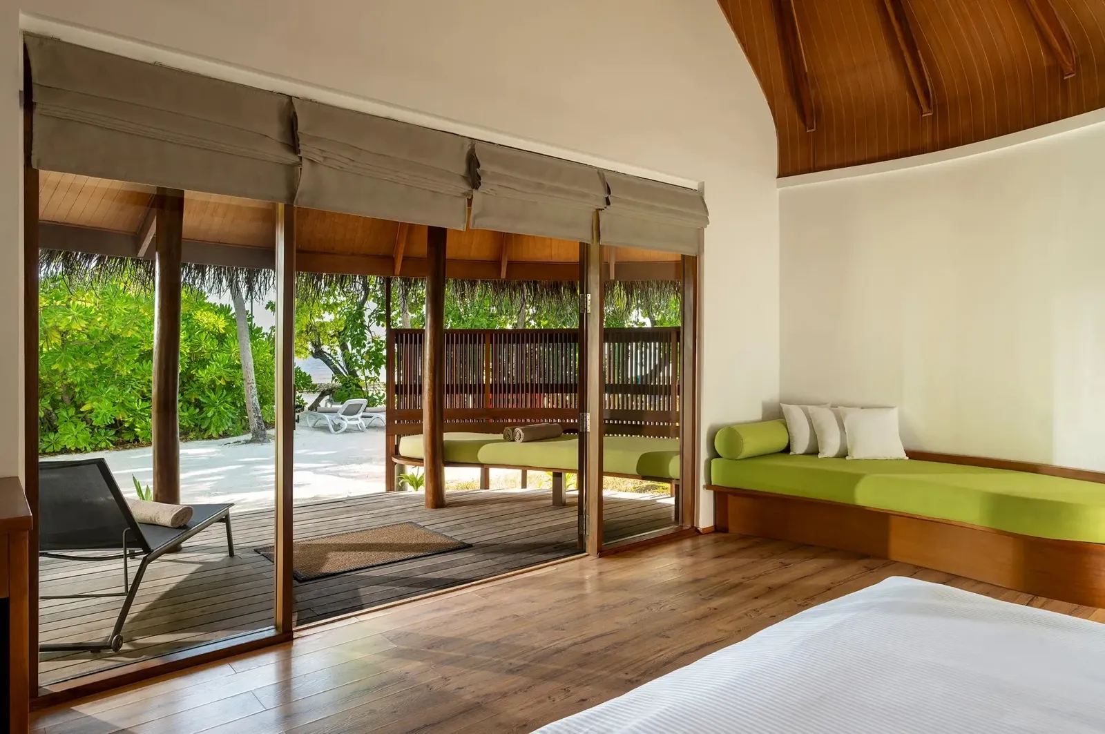 Inside a Superior Beach Villa, the low bed and the glass doors open onto the deck and the garden