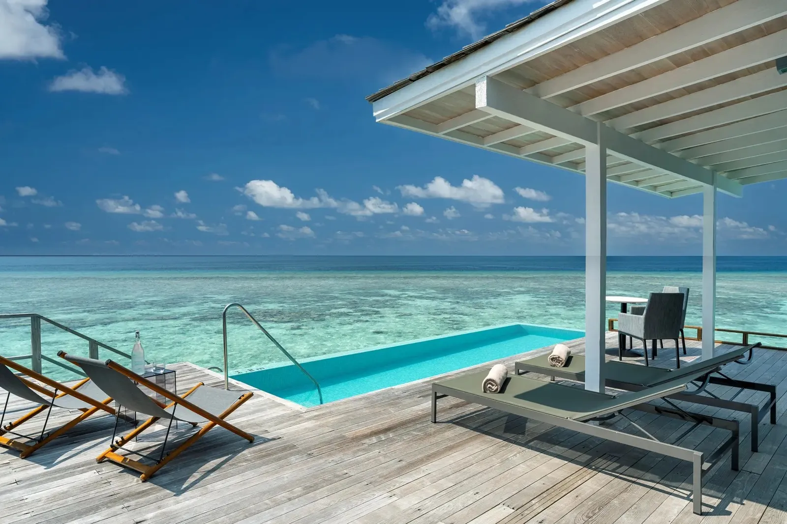 A Thundi Water Villa’s deck with its infinity pool, the loungers and the reef under the surface