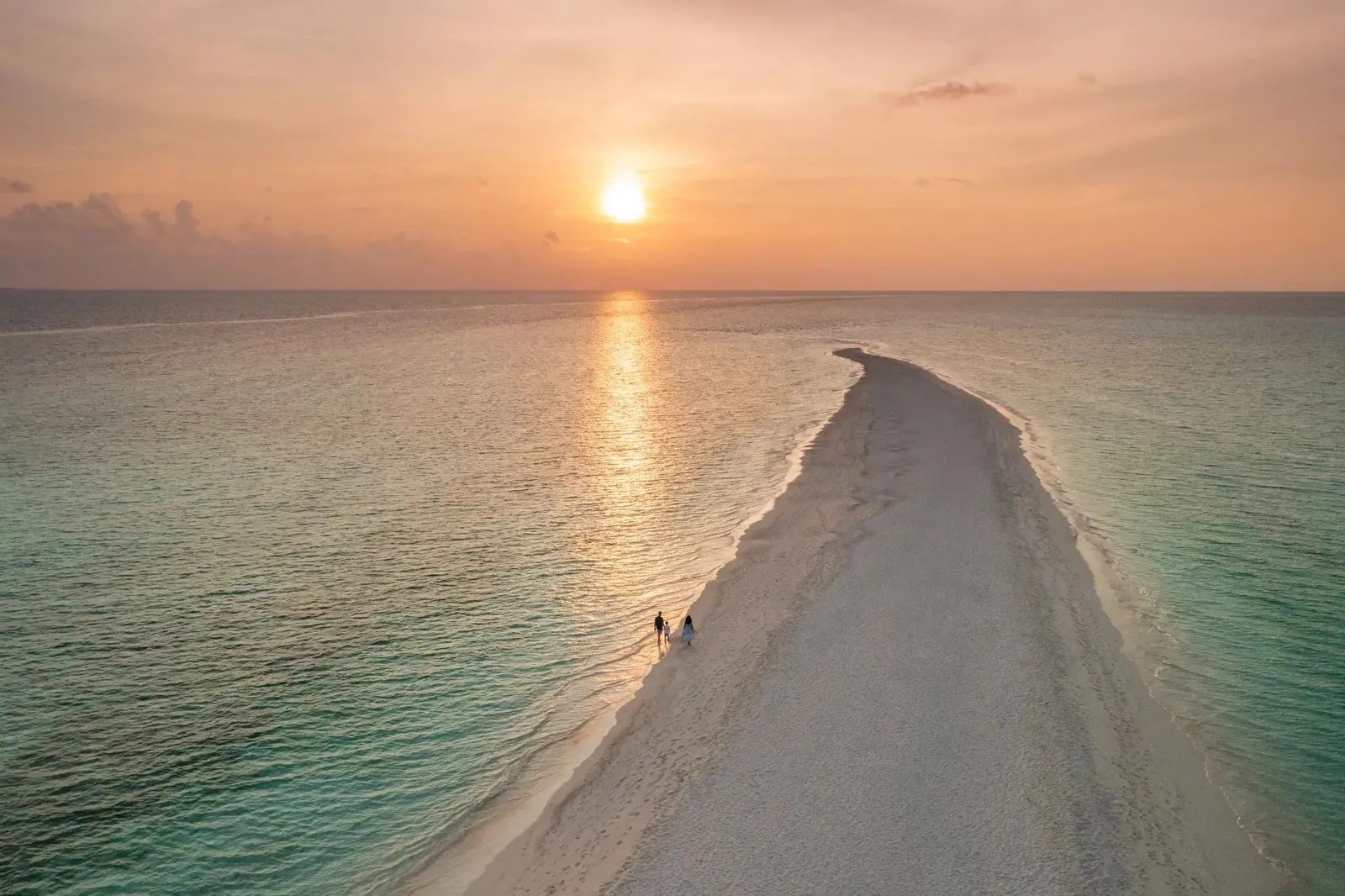 Kuramathi’s sandbank running out to sea at sunset, 2 people walking along its edge