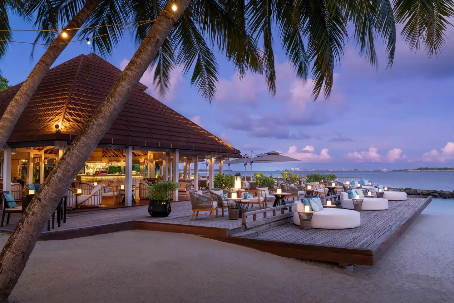 The Kandu Bar’s deck at dusk, on the beach among the palms