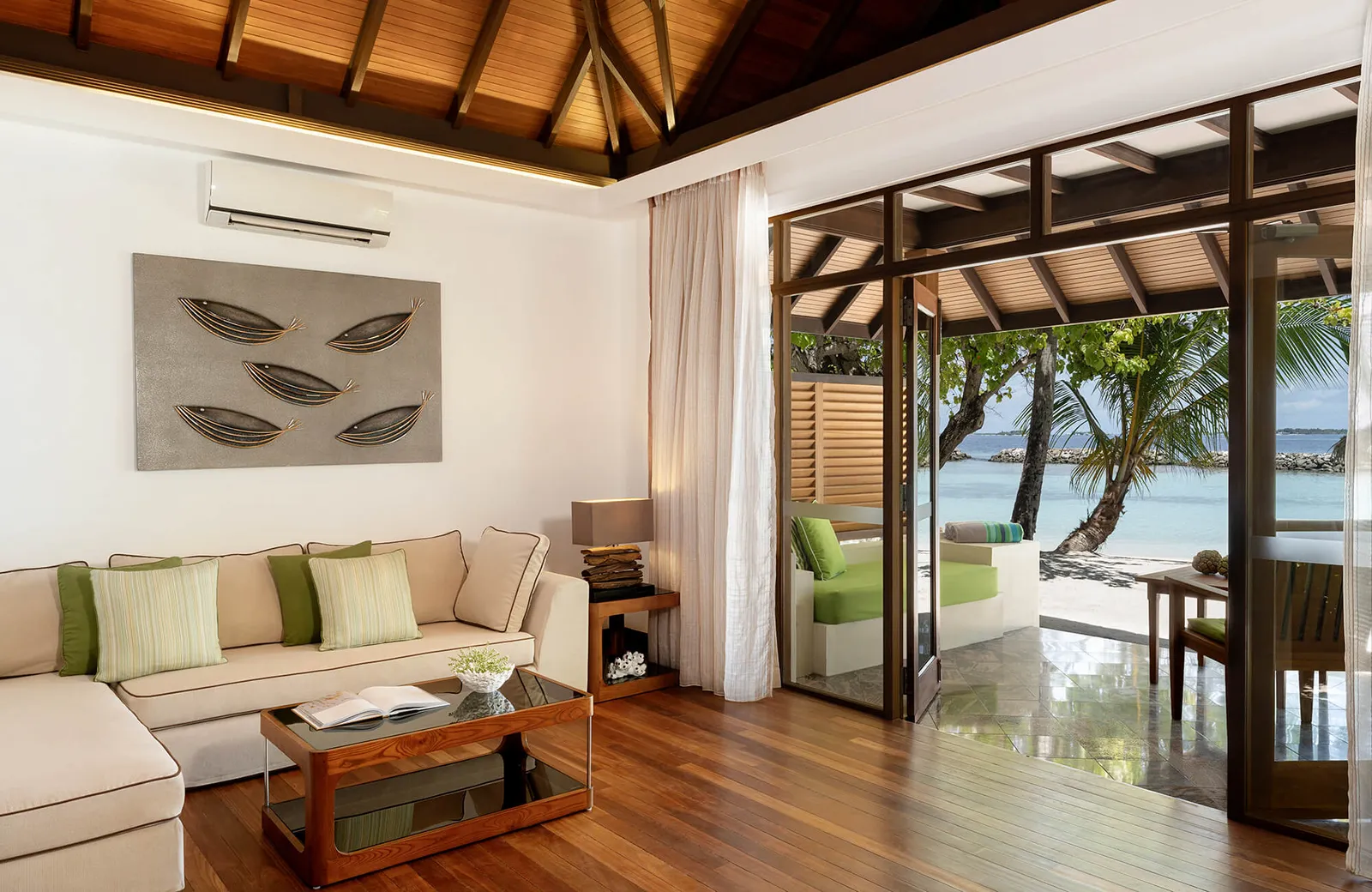 A Beach Villa living room with its U-shaped sofa, the beach beyond the glass
