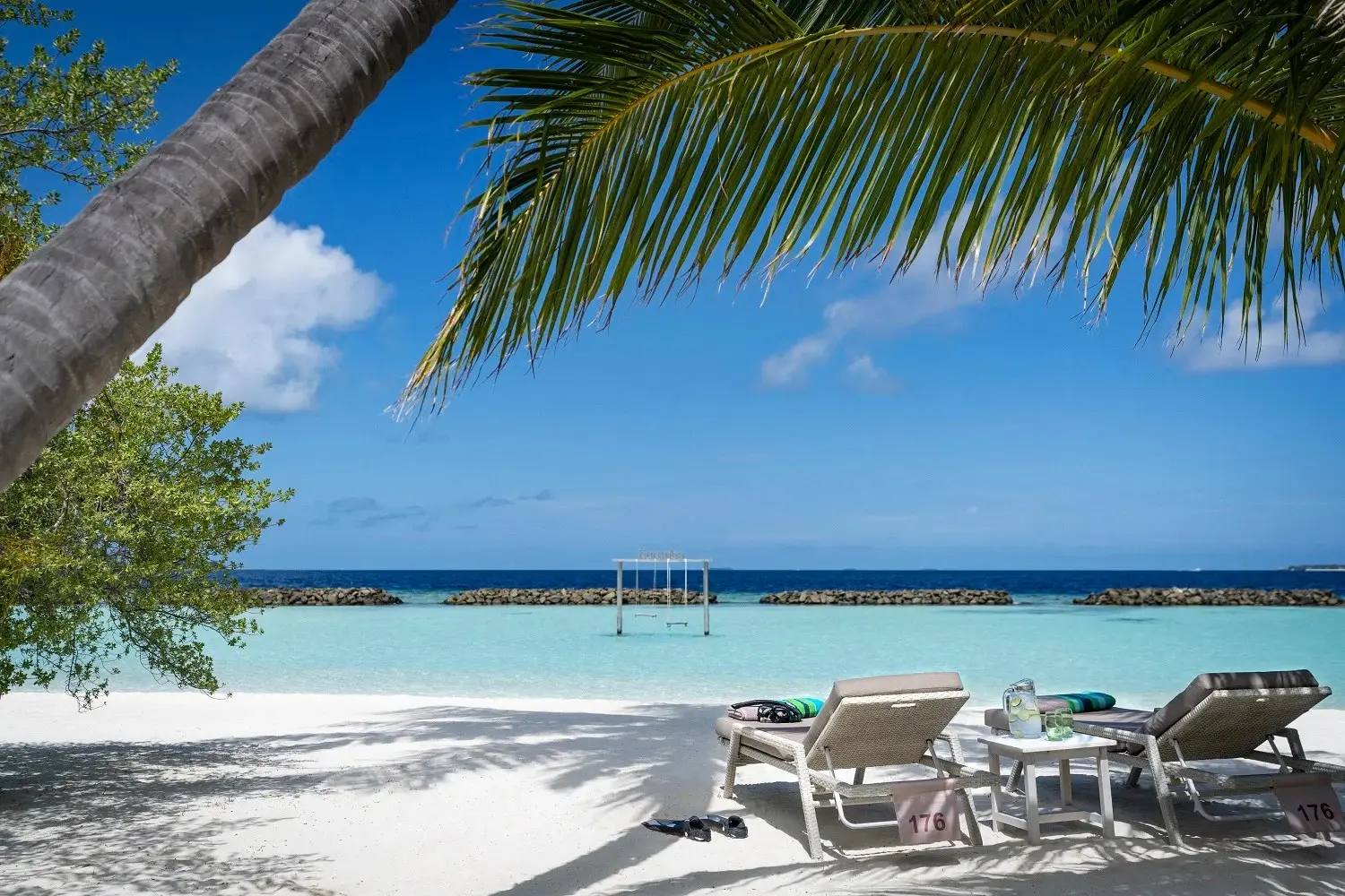 A Beachfront Deluxe Bungalow’s terrace, loungers and the beach ahead