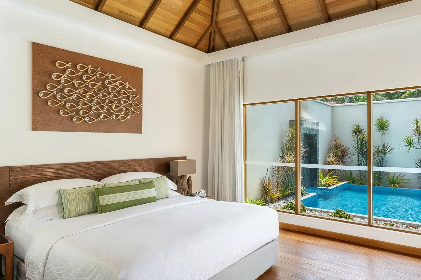 A Deluxe Pool Villa bedroom, the pool beyond the glass