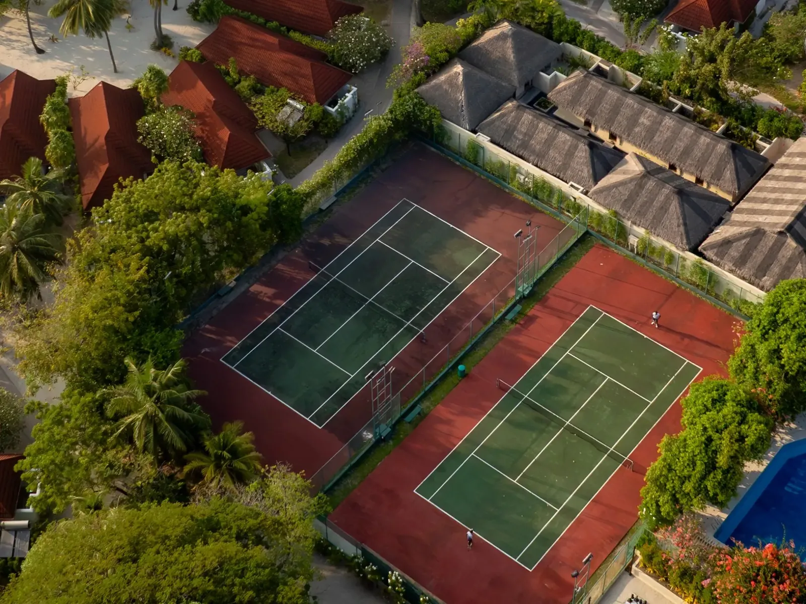 The tennis courts from the air among the trees and red roofs