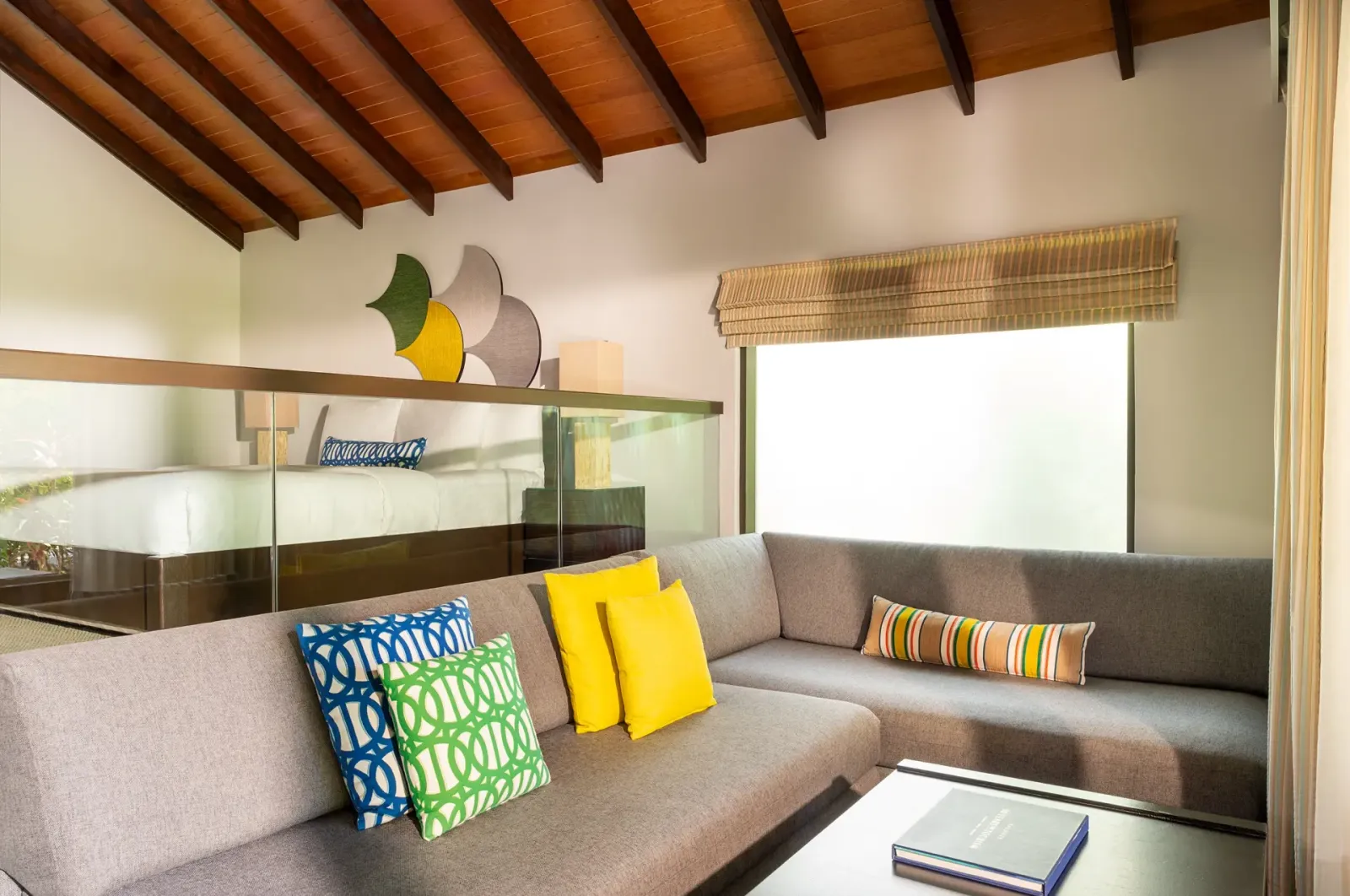 Il soggiorno di una Deluxe Villa, con il divano sotto il soffitto di legno e il letto sul soppalco.