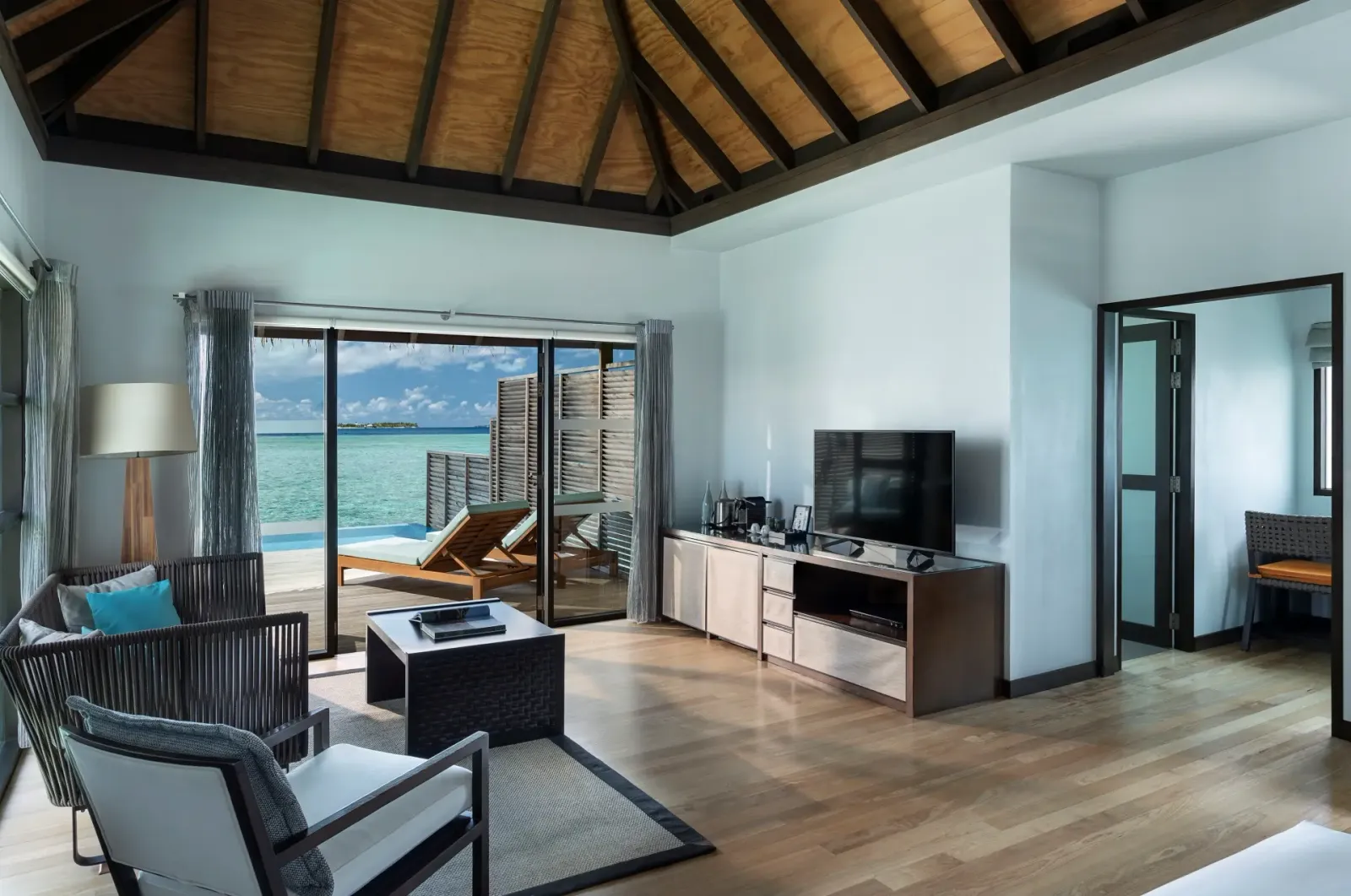 Il soggiorno di un Water Bungalow with Pool, aperto sulla terrazza con la piscina e la laguna.