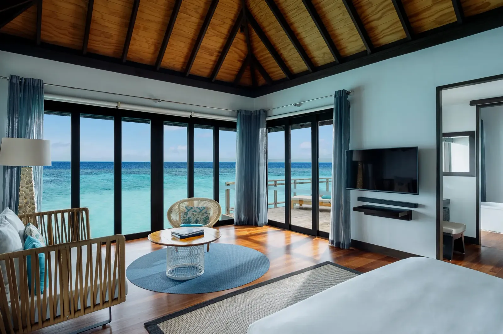 Una Water Villa: le vetrate dal pavimento al soffitto sulla laguna e il salotto davanti al letto.