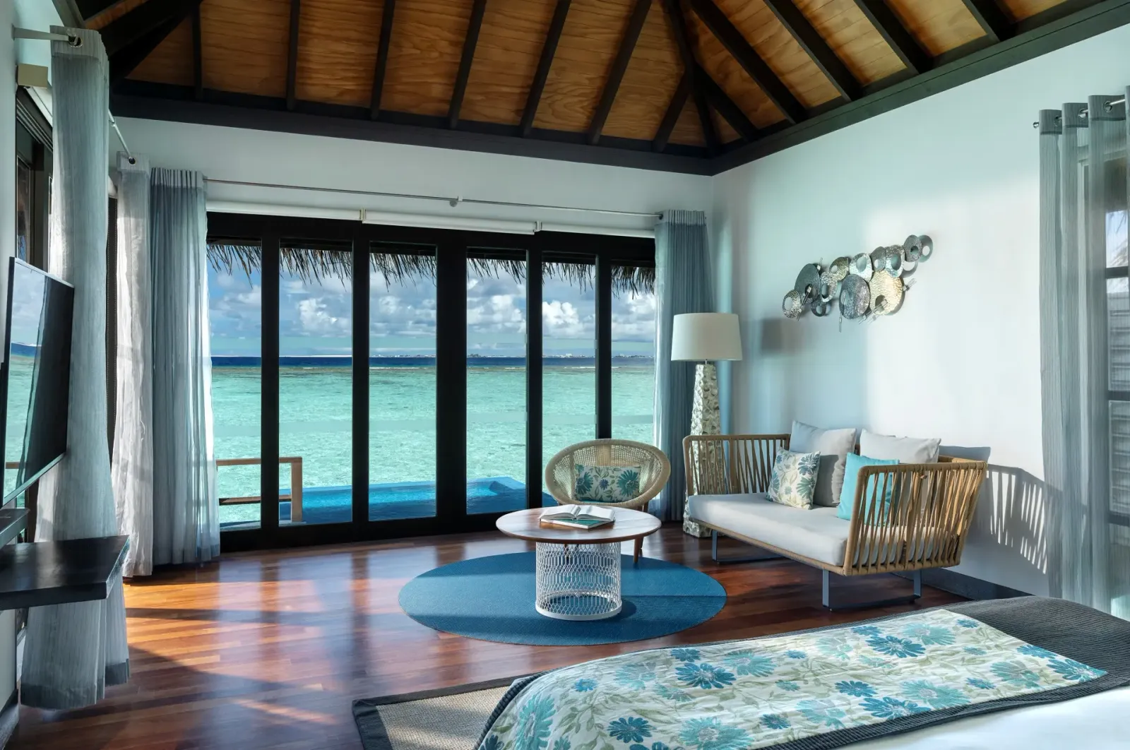 Una Water Villa with Pool, il letto e il salotto davanti alle vetrate, la piscina oltre il vetro.