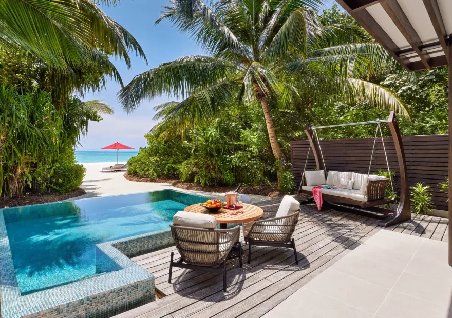 The deck of a beach pool villa, with its table and shaded swing seat