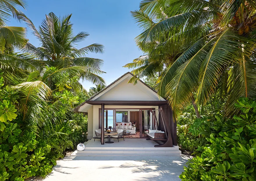 The entrance to a beach villa among the palms, with its terrace and swing seat