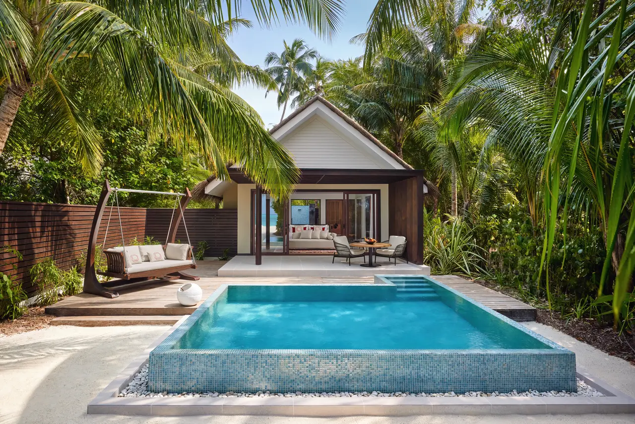 A Deluxe Beach Pool Villa with its pool in front, among the palms