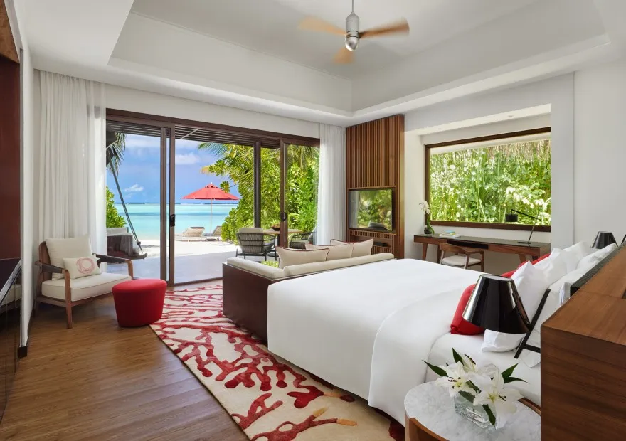The bedroom of a Deluxe Beach Villa, glass doors open to the beach