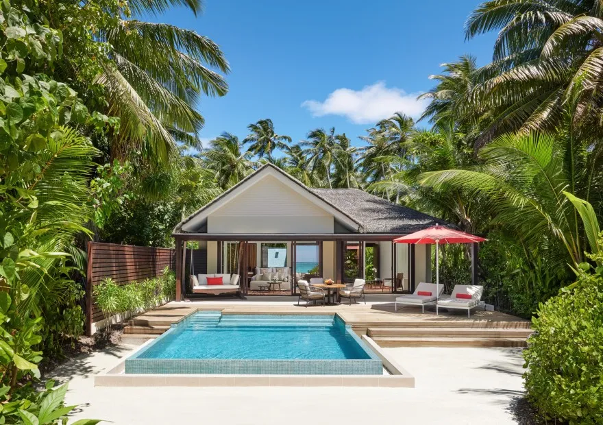 A family beach pool villa, with loungers and a red parasol