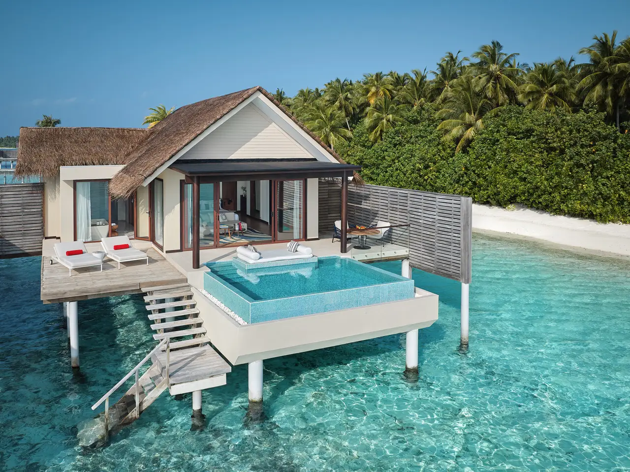 An overwater villa with a pool on its deck and steps down into the lagoon