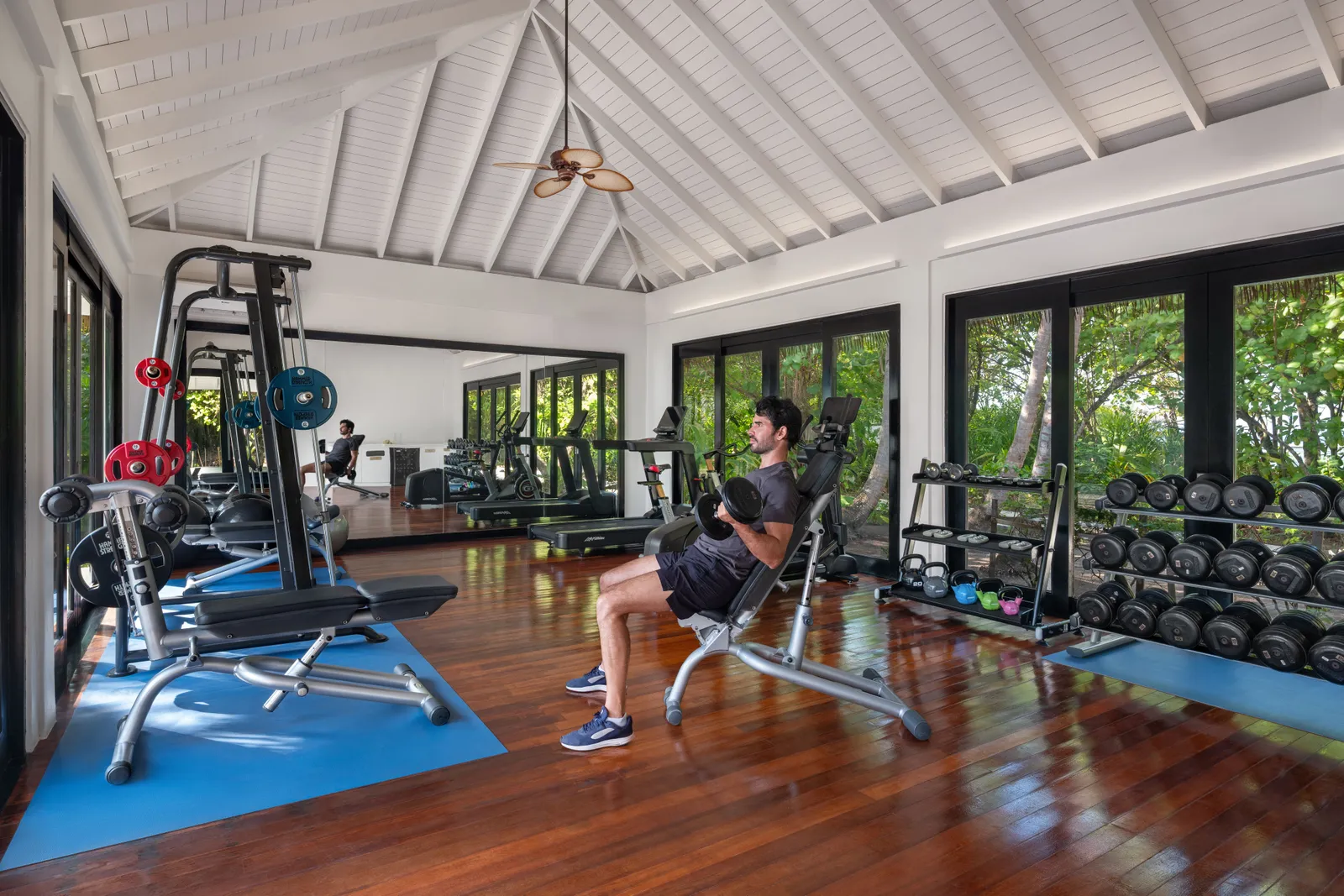 The gym, with its white timber ceiling, the weights and machines, and the windows onto the green.