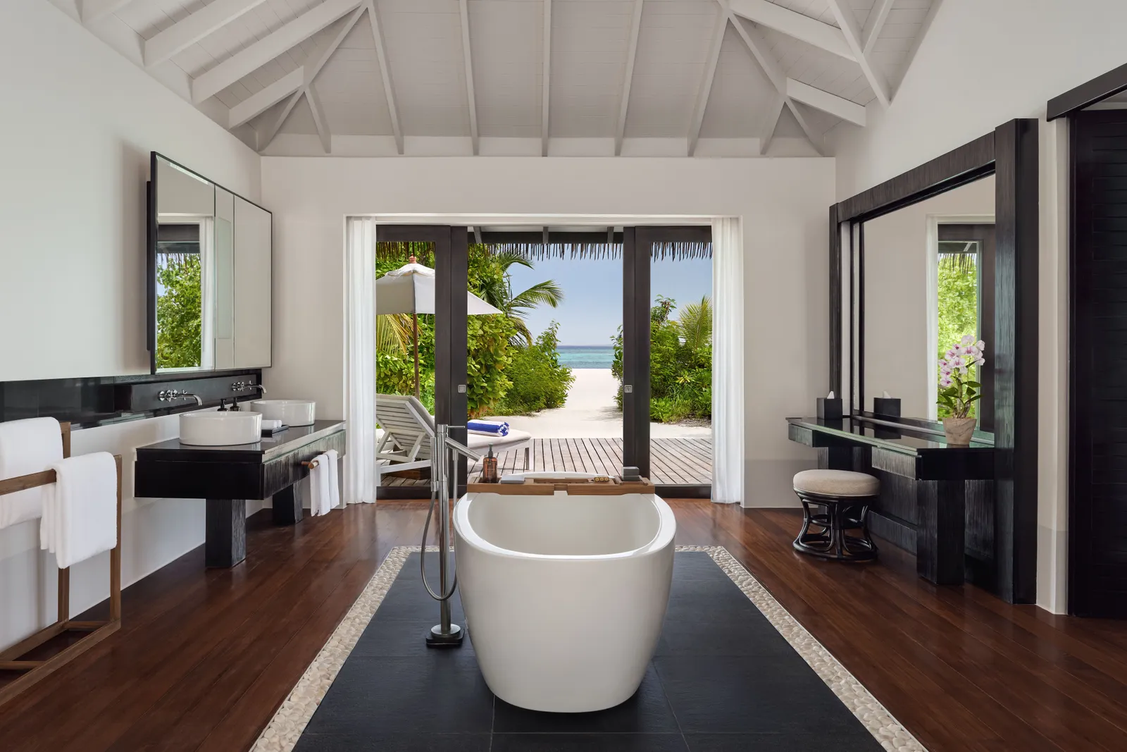 A beach villa bathroom, with the freestanding tub in the middle and the door open onto the path to the sand.