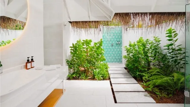 The Sunset Beach Villa open-air bathroom, with a white basin, plants and outdoor shower.