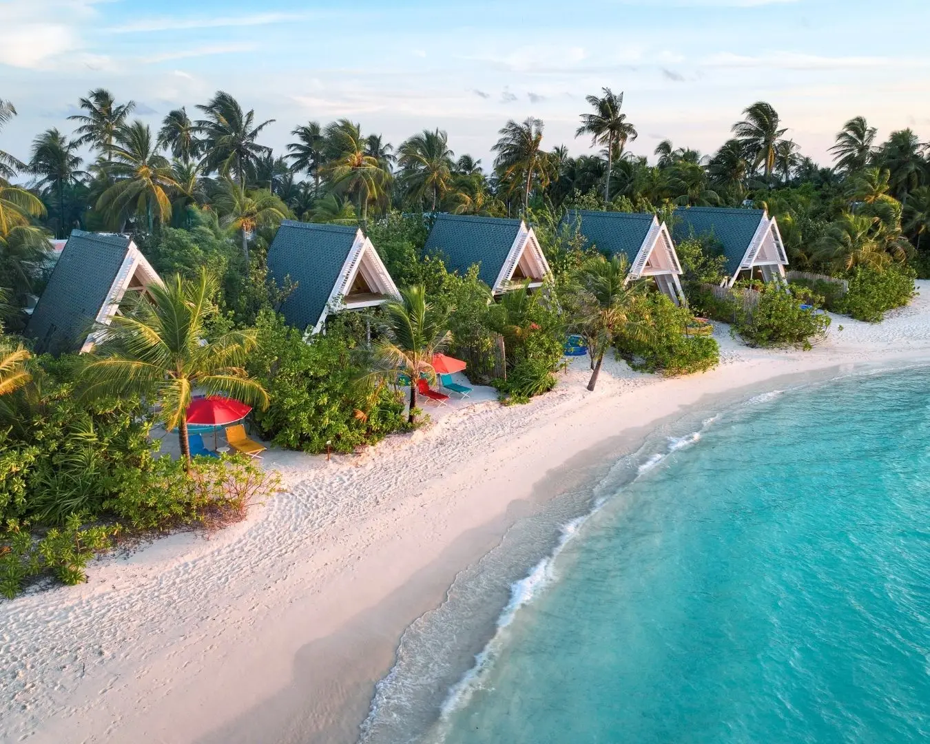 The A-frame villas among the palms, facing a white beach and turquoise water.