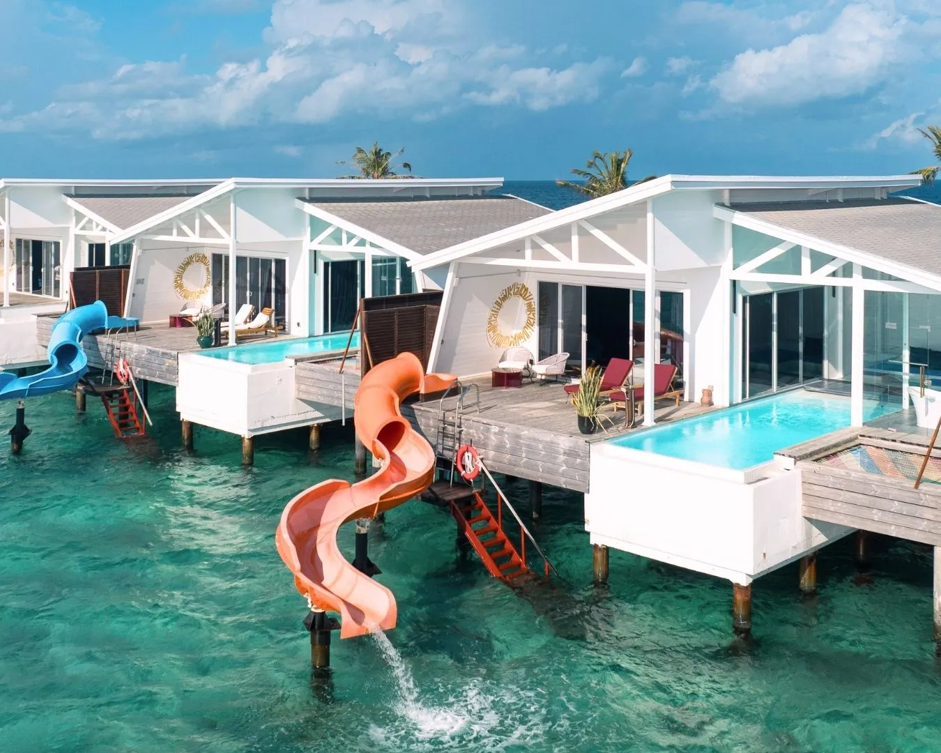 The Odi Water Villas on the lagoon: decks with pools and orange slides running down into the sea.