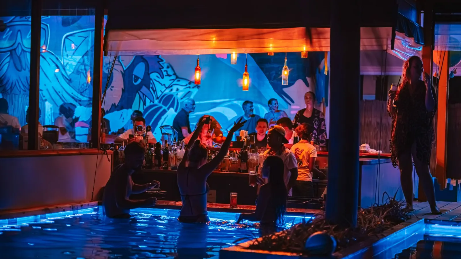 Sobi Bar in the evening: guests at the swim-up counter, beneath blue murals.