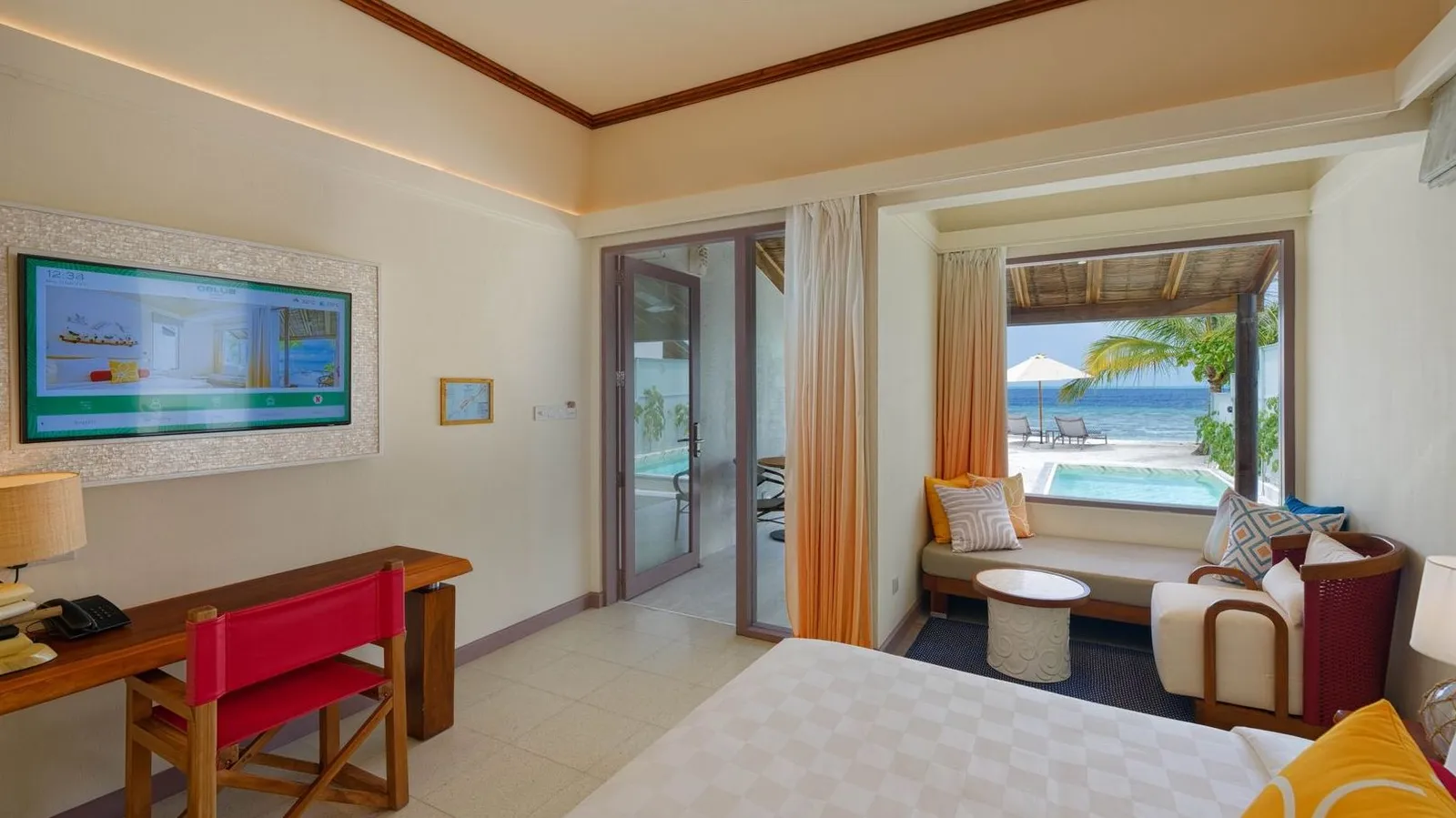 The bedroom of a Deluxe Beach Villa with Pool, with the bed, a desk and a window on to the pool