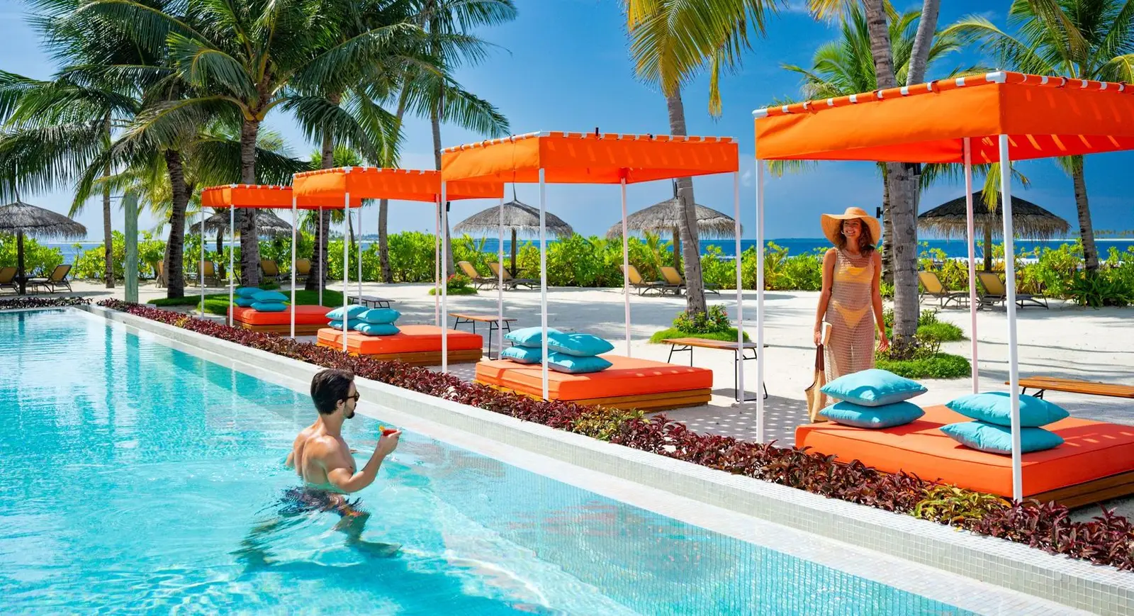 One Banyan’s adults-only pool, with orange cabanas along the edge and a guest swimming.