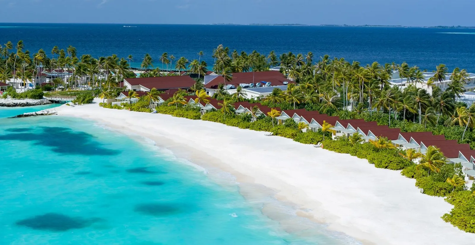 The island’s white beach from above, Beach Villas among the palms and the turquoise lagoon.