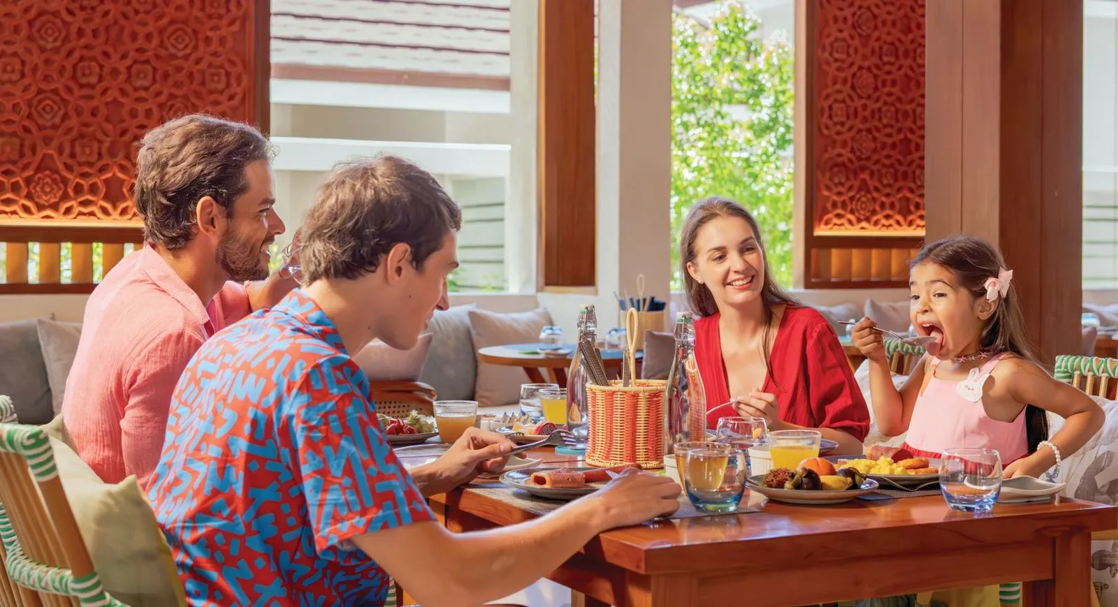 A family at table in Element X, the little girl biting into fruit from the buffet.