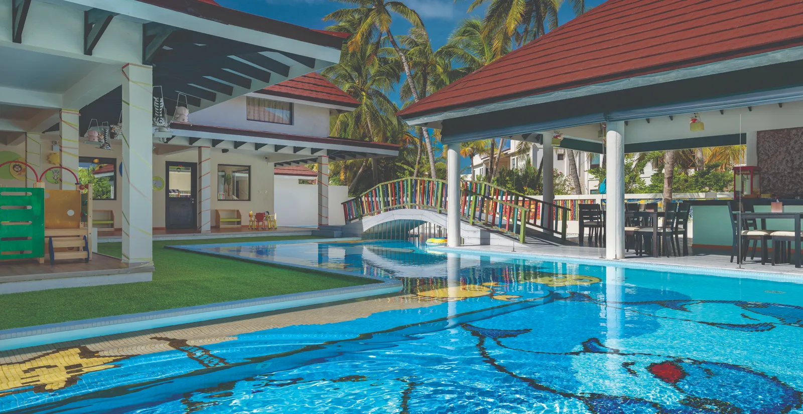 The Kids X Camp pool, its mosaic floor, a brightly painted footbridge and the club’s pavilions.