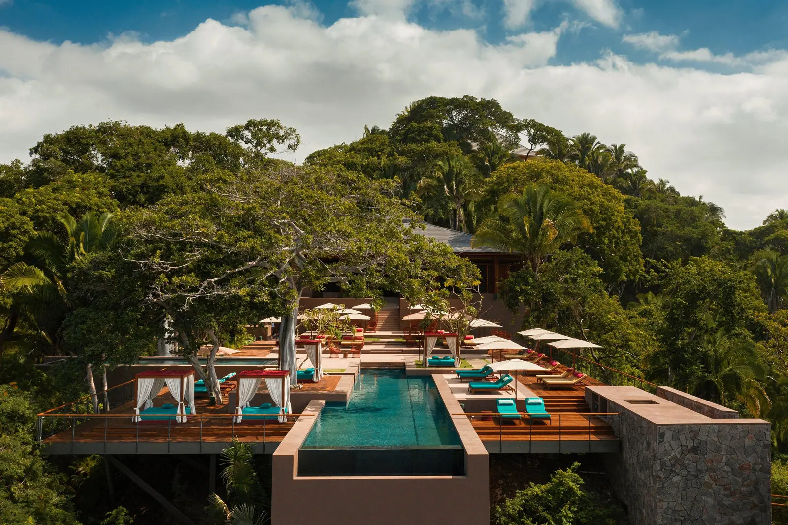 Alma’s pool with loungers, cabanas and surrounding forest