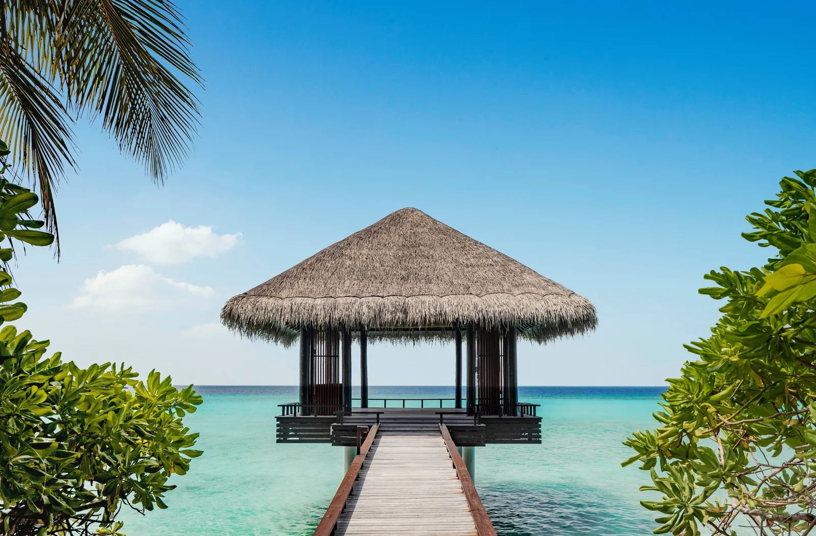 A wooden jetty leading to a thatched pavilion on the lagoon